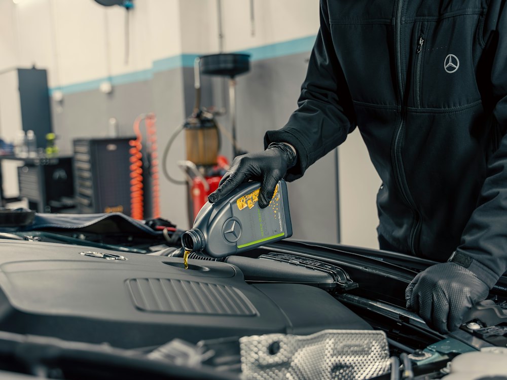 Mechanic pouring oil into a car engine (stock photo)